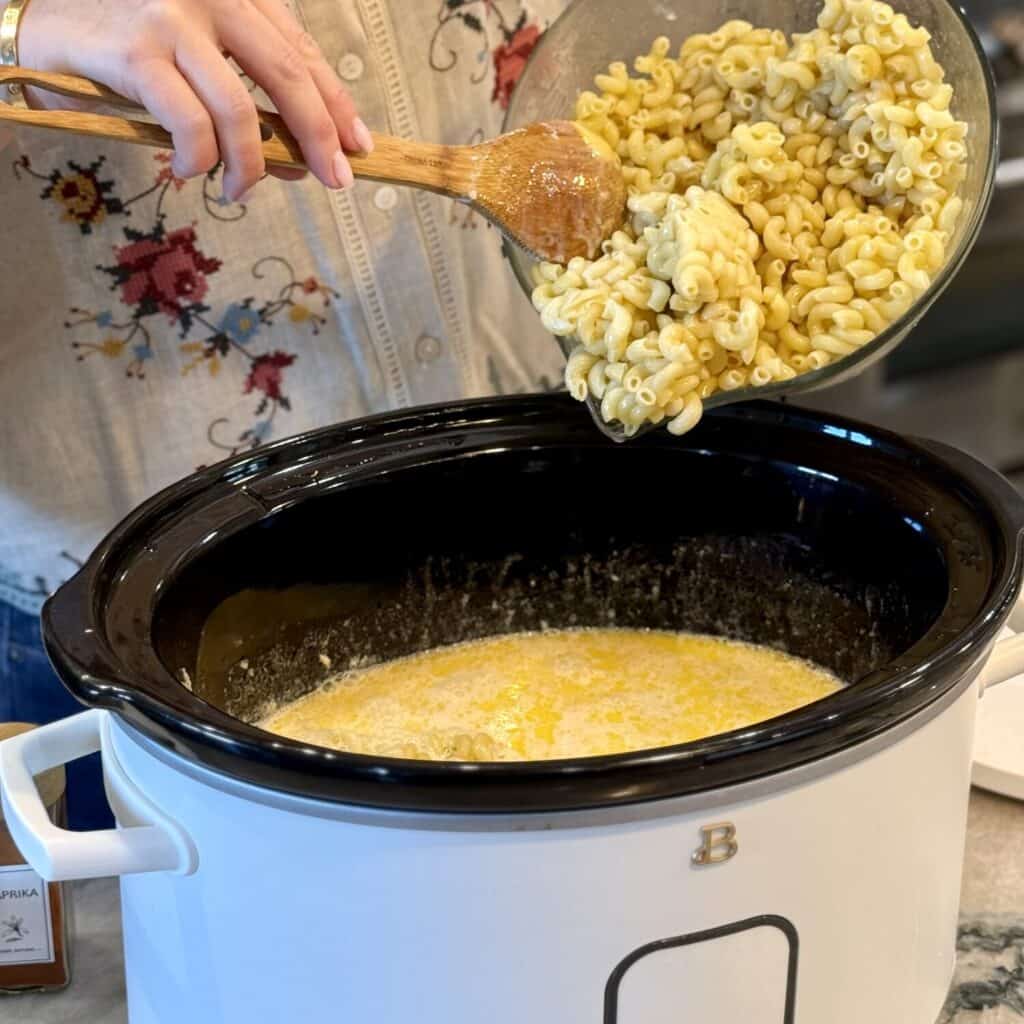 Adding pasta to a crockpot.