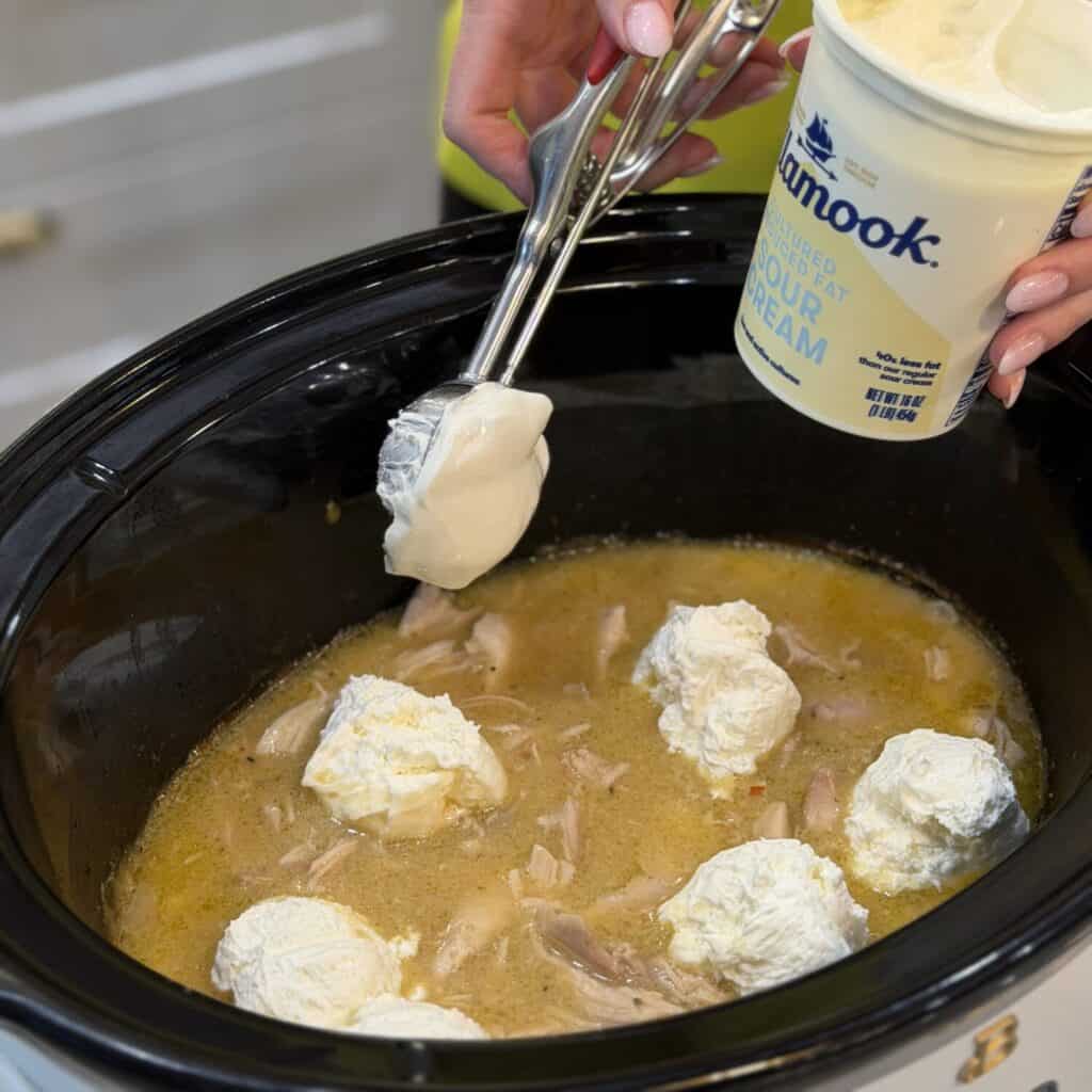 Adding sour cream to crockpot.