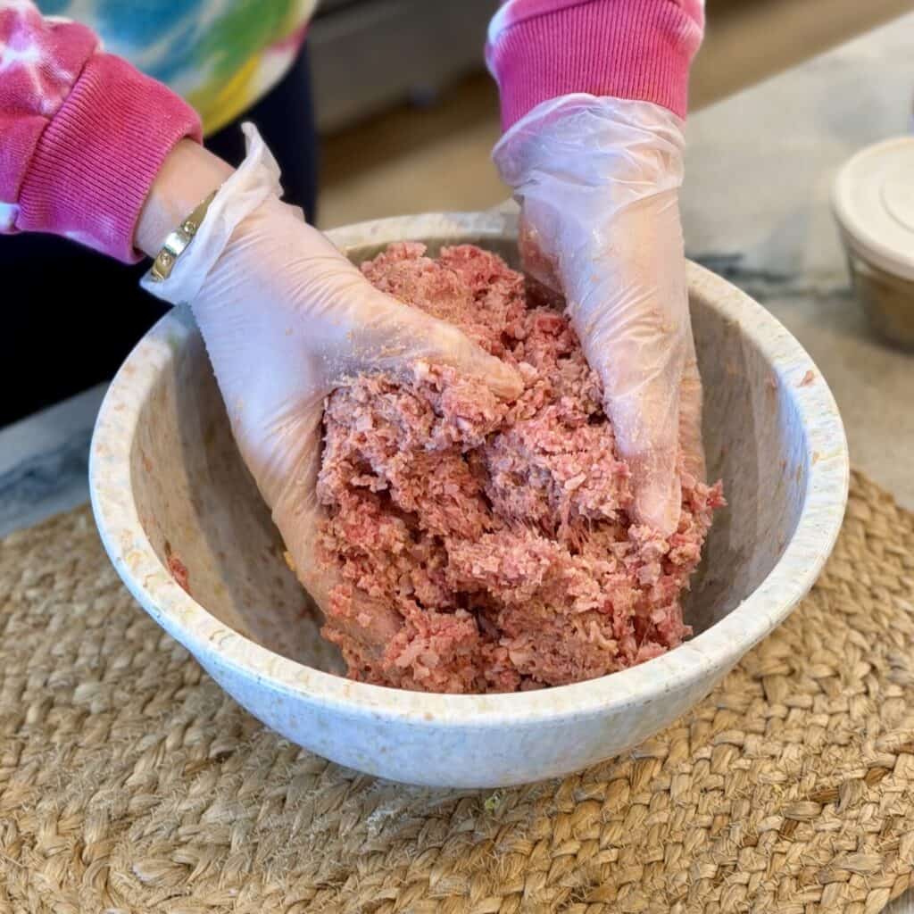 Mixing meat in a bowl for ham balls.