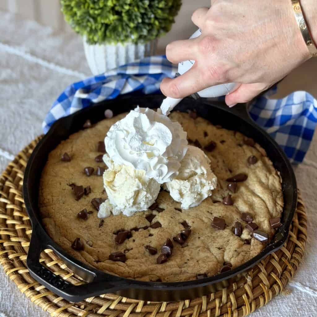 Adding whipped cream onto the cookie skillet.