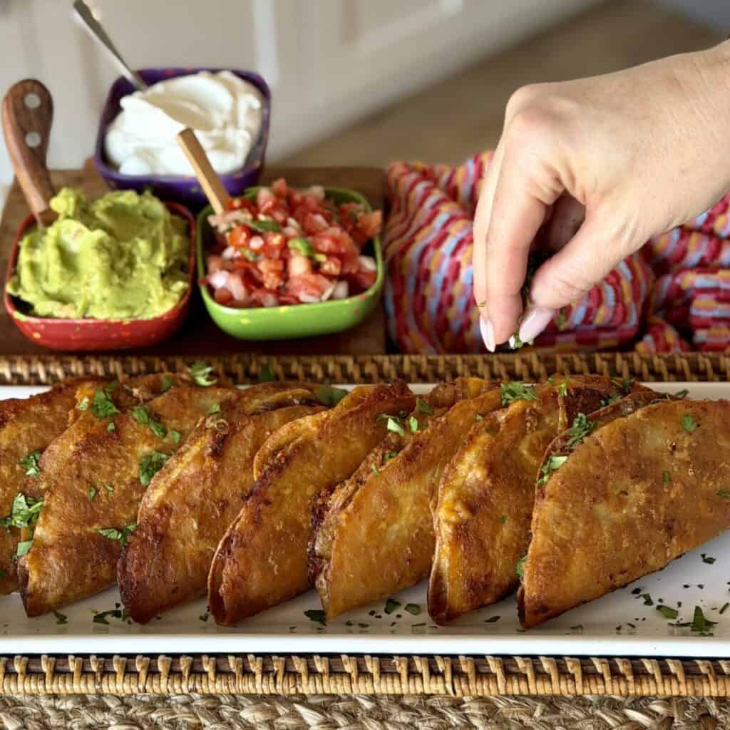 Sprinkling cilantro on sheet pan tacos.