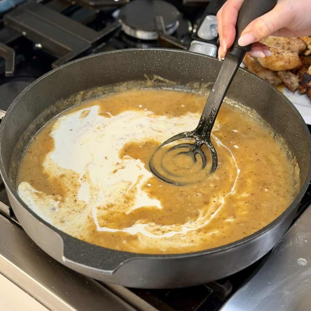 Stirring in cream to the pan.