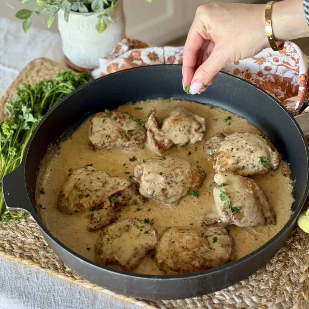 Garnishing the pan of peppercorn chicken.