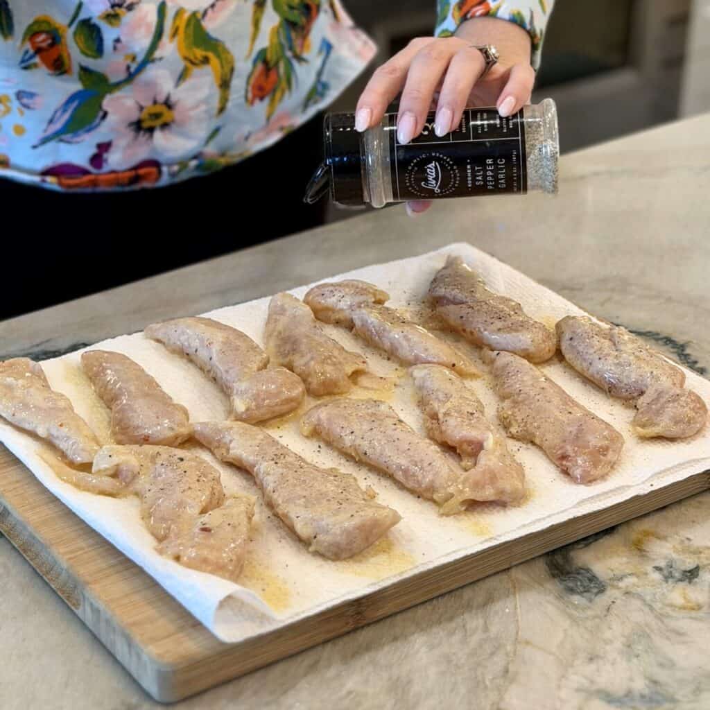 Seasoning the chicken on the paper towel.