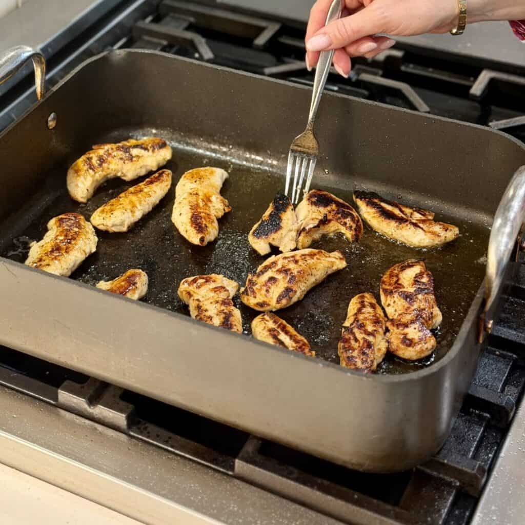 Flipping the chicken to fry on the Pan.