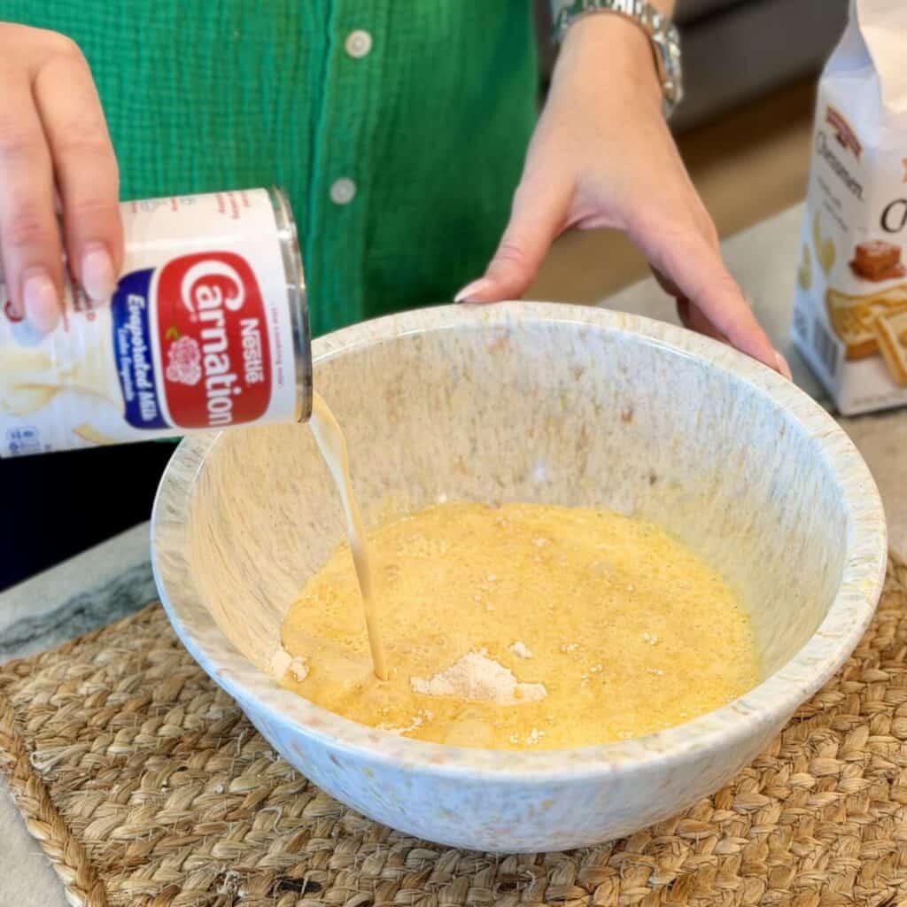 Adding condensed milk to the bowl.