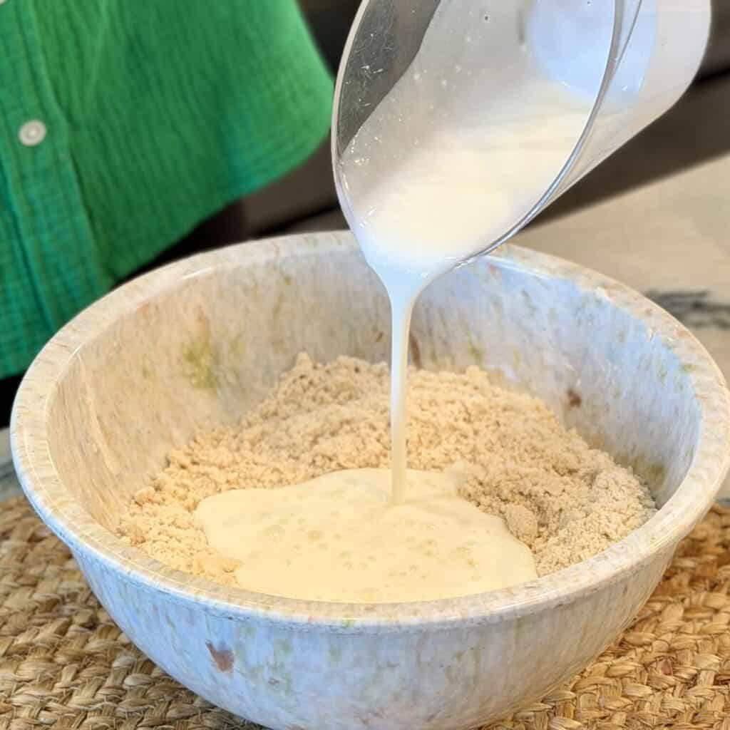 Adding buttermilk to the Bowl of dry ingredients.