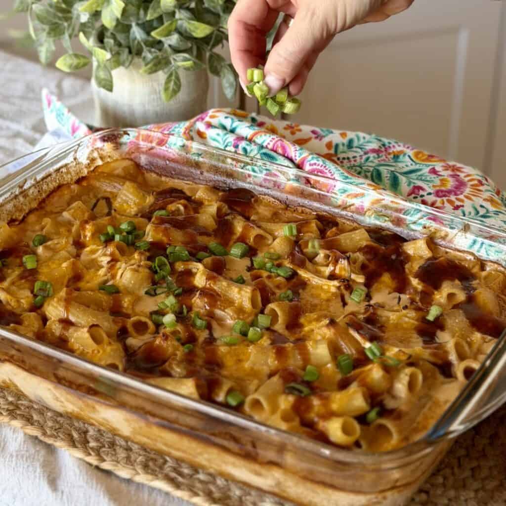 Adding green onions to the pan of Barbecue Chicken Casserole.