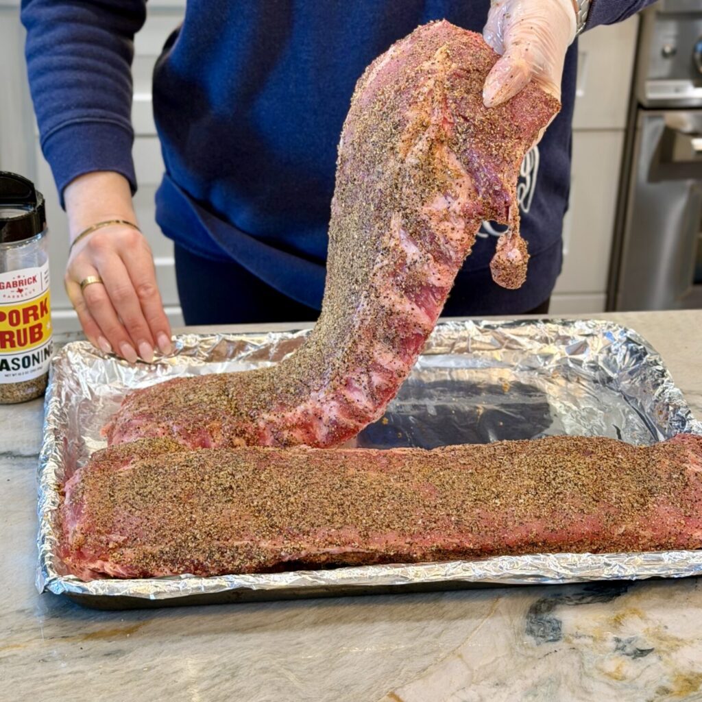 Adding seasoned ribs to a pan.