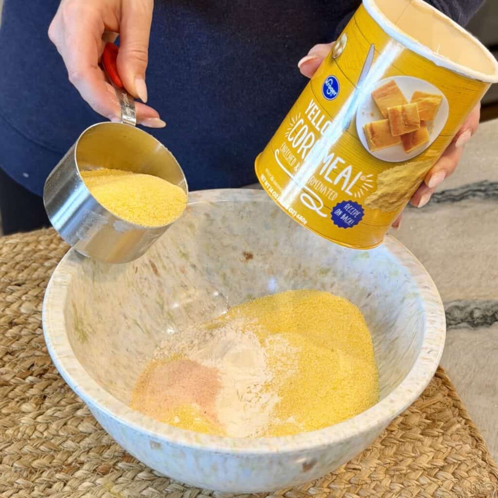 Adding cornmeal to dry ingredients.