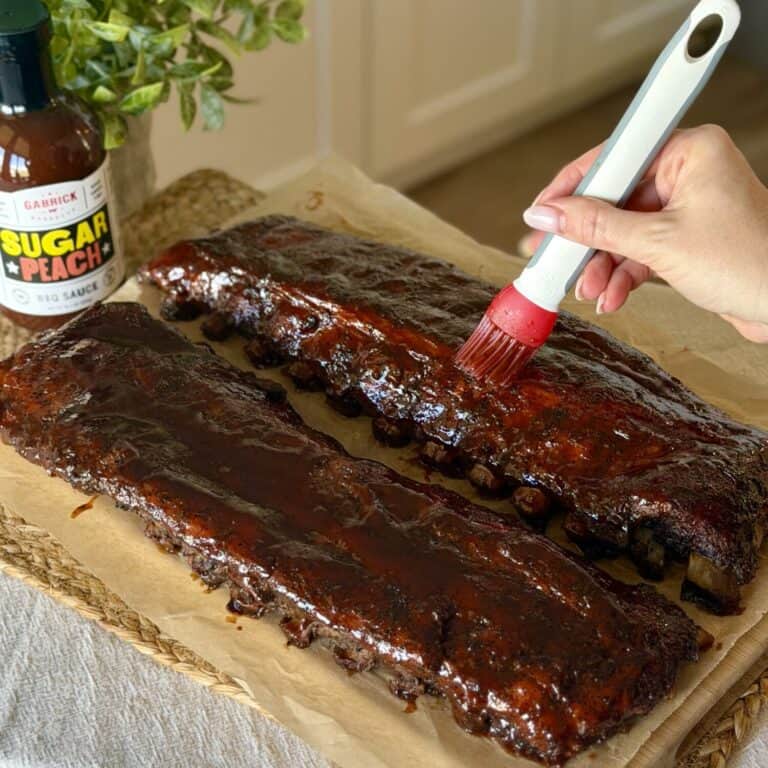 Adding barbecue sauce to rack of ribs.