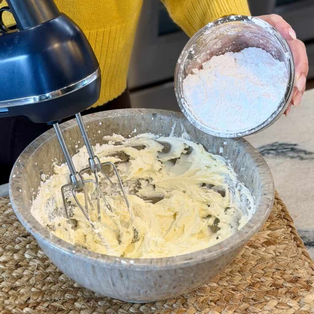 Adding powdered sugar to the whipped cream.