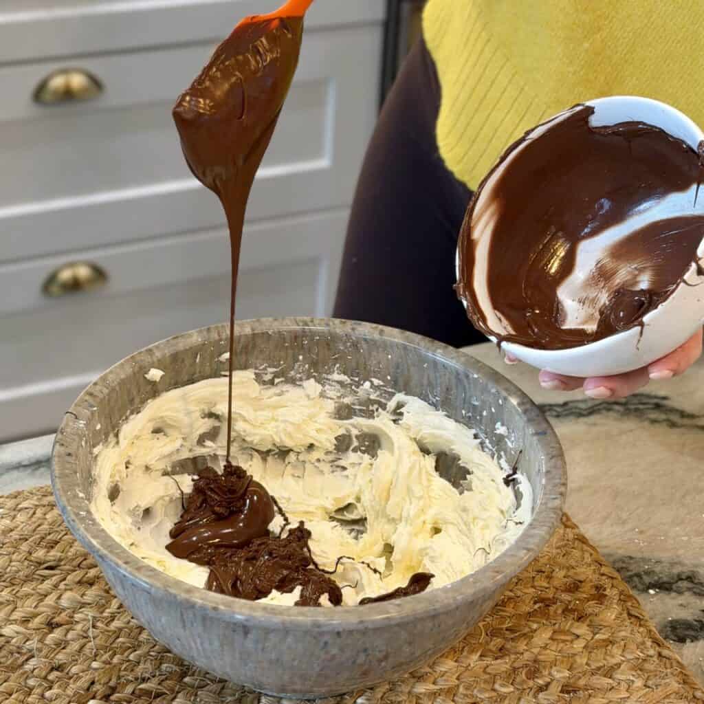 Adding melted chocolate to the whipped cream.