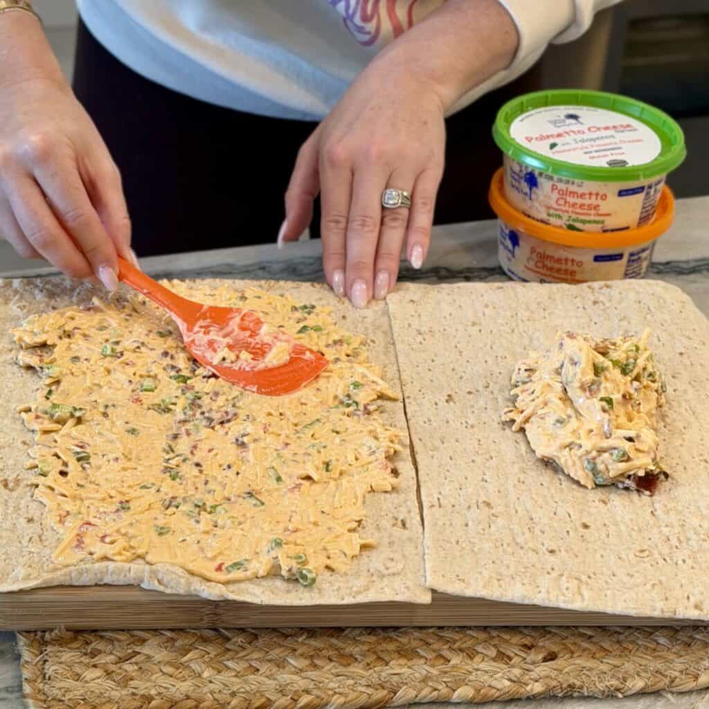 Spreading the filling on a wrap for pimento cheese pinwheels.