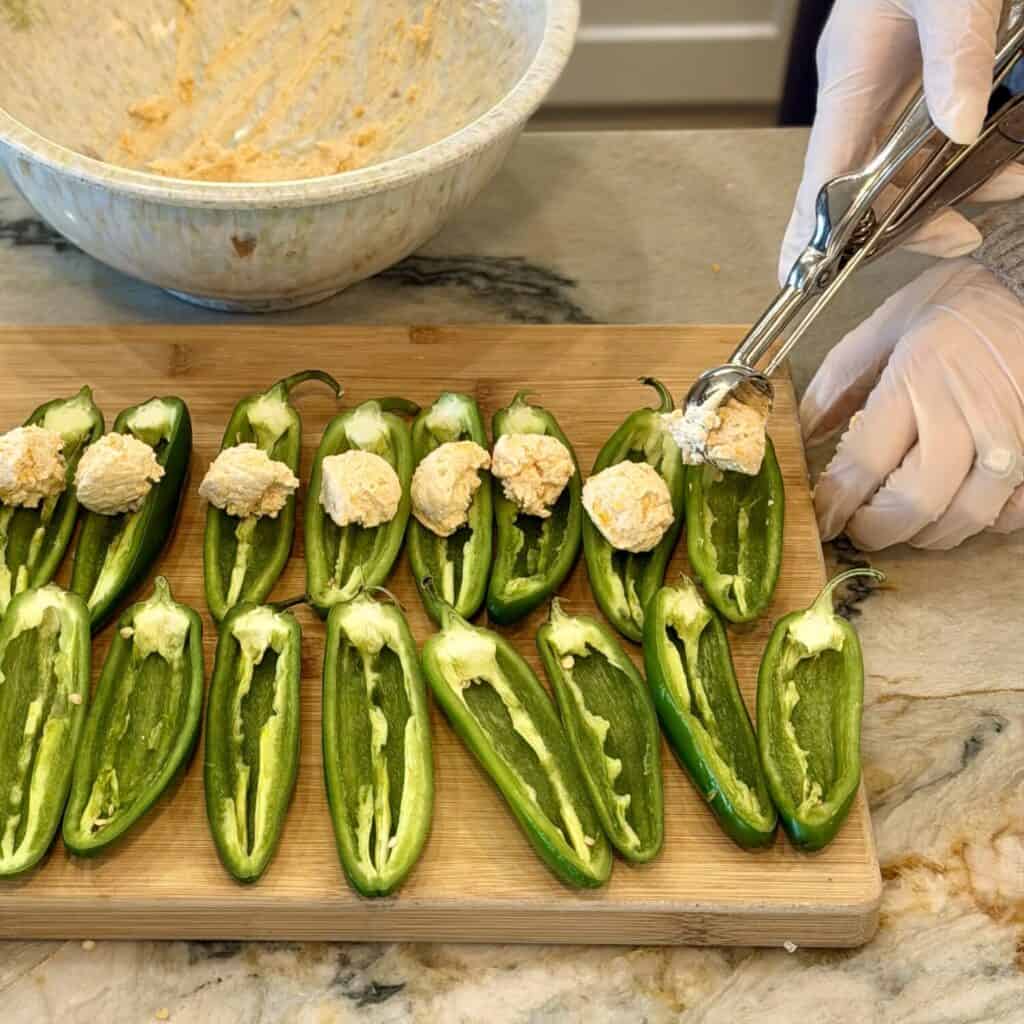 adding in the filling to the jalapeno poppers.
