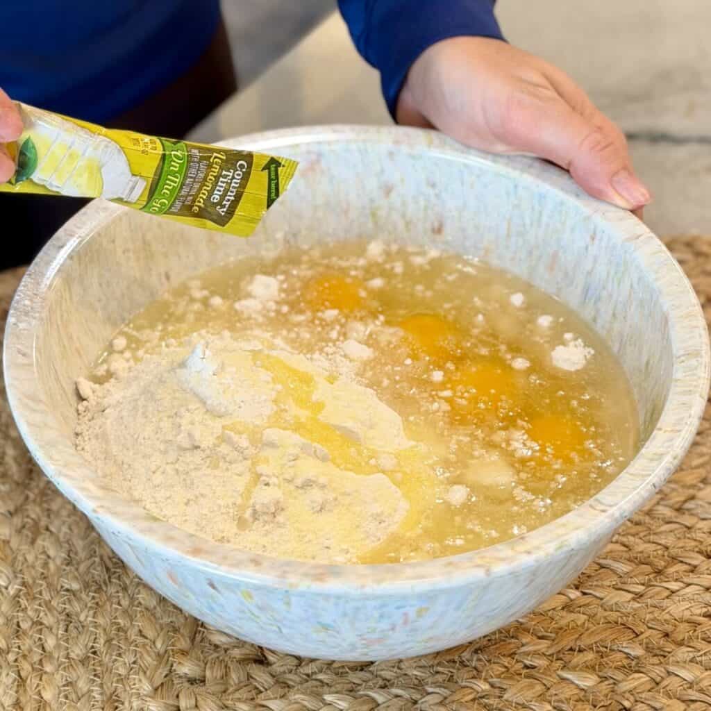 Adding lemonade mix to the cake mix bowl.