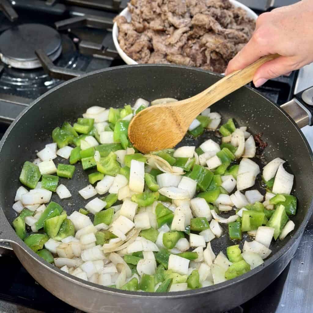 Sautéing onion and pepper on the pan.
