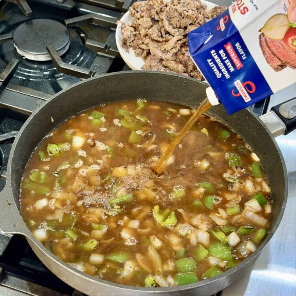 Adding chicken Broth into the pan.