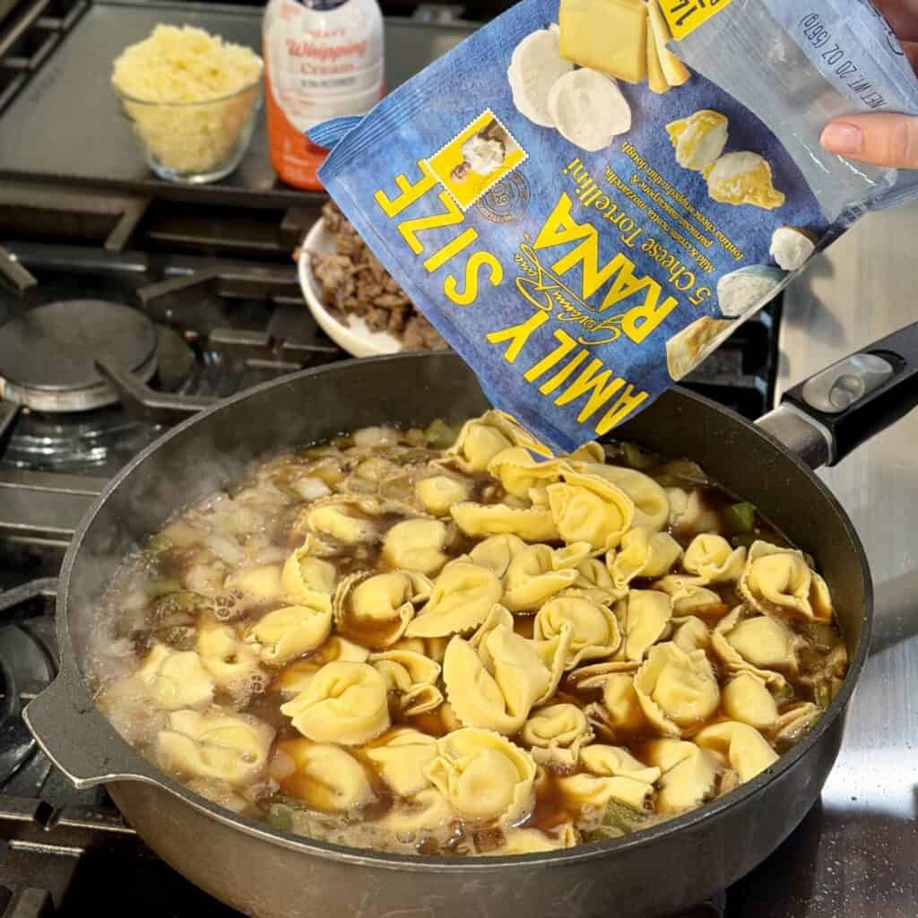 Adding tortellini to the pan.