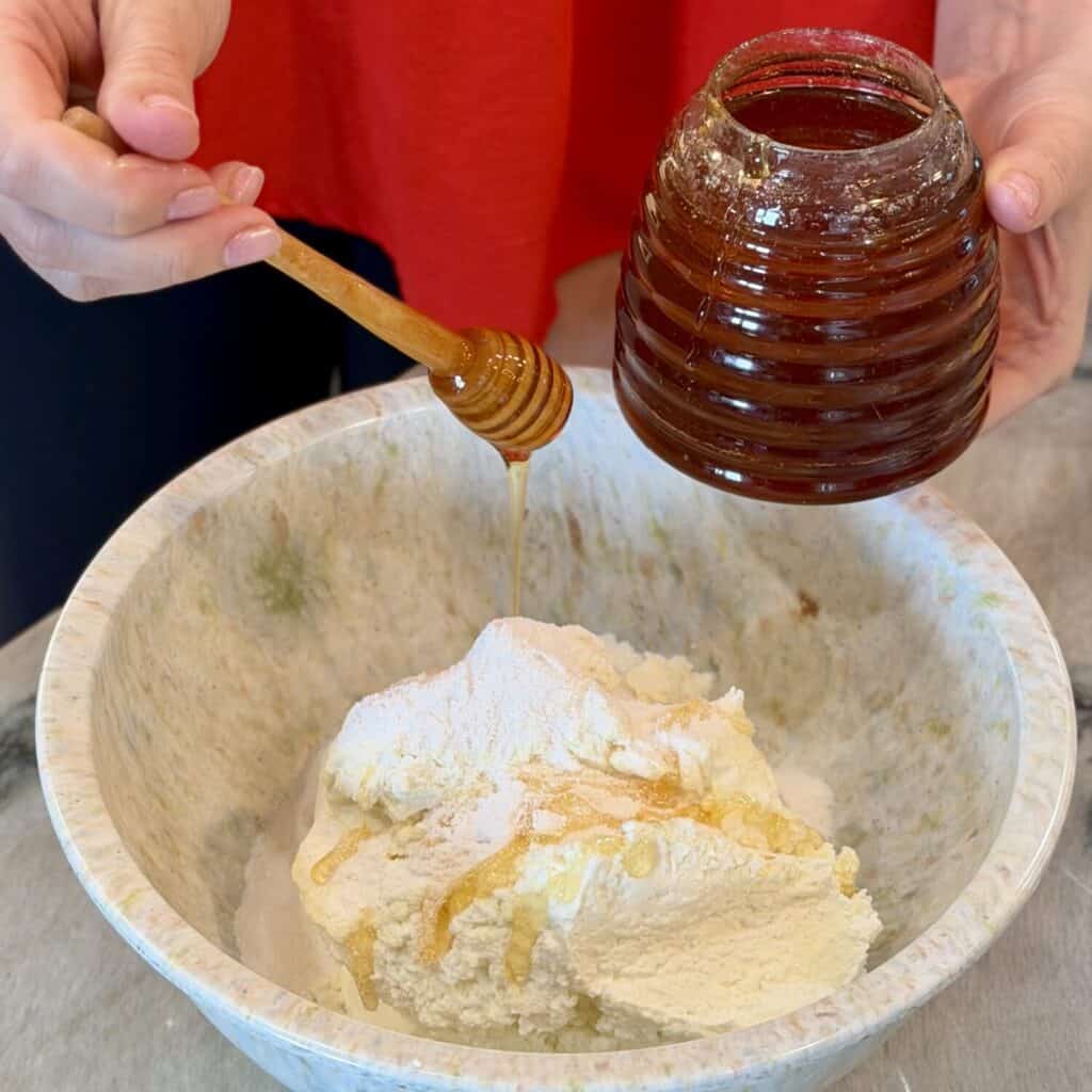 Adding honey to the bowl of cheese.
