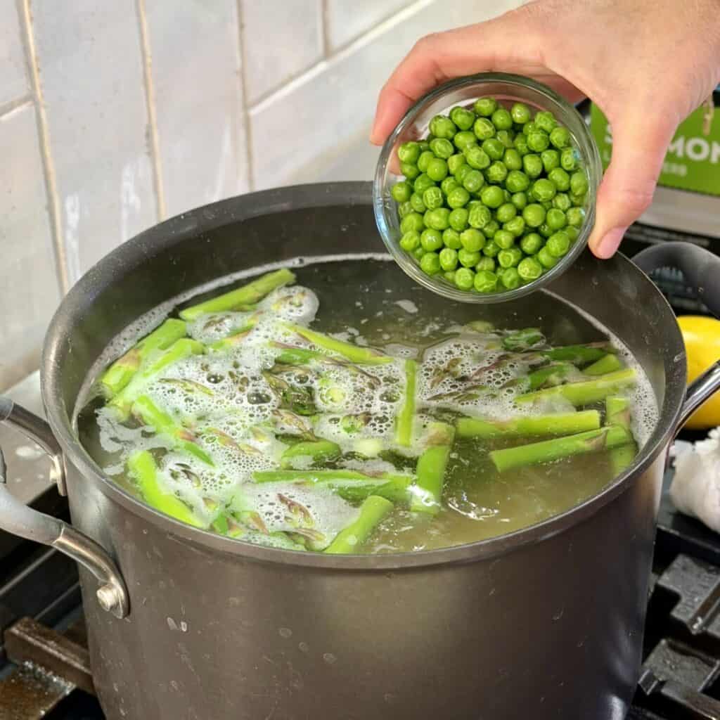 Adding peas to a pot of boiling water.