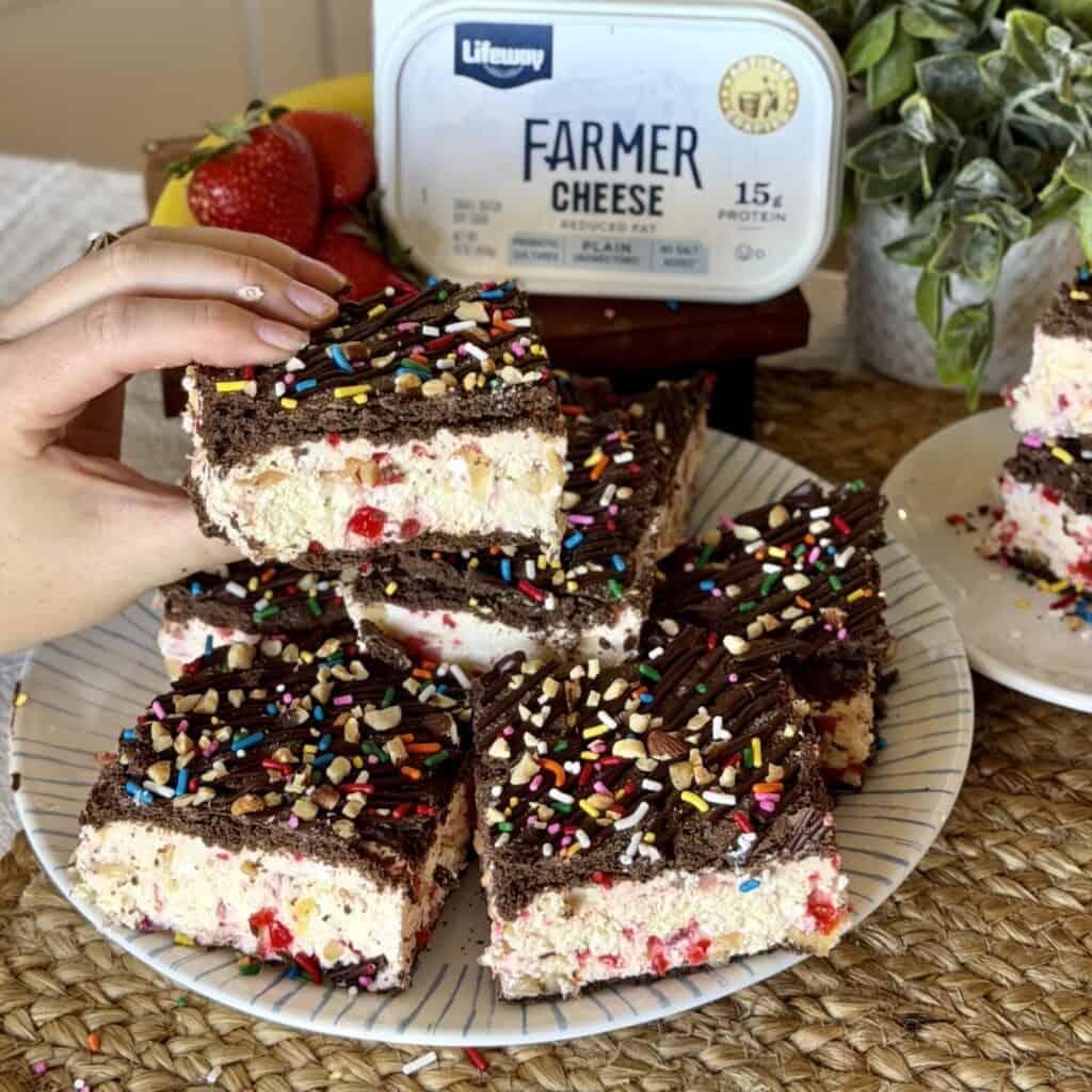 Holding a banana split ice cream sandwich.