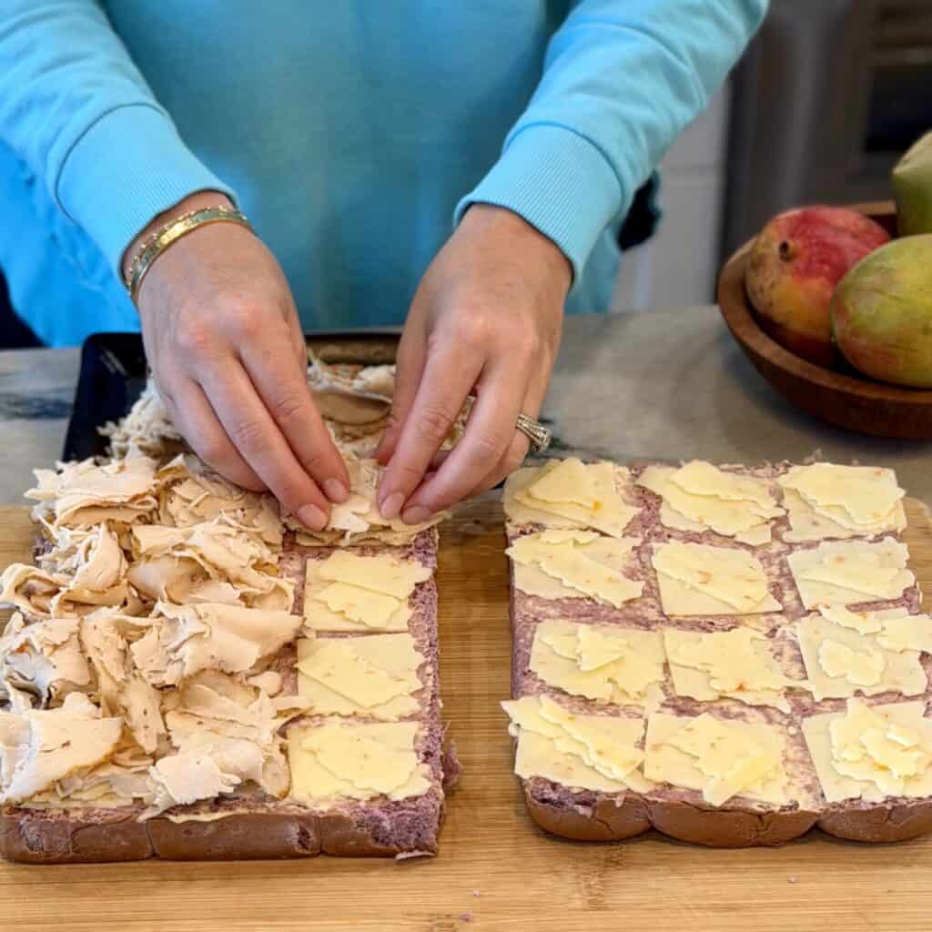 Adding deli chicken and cheese to sliders.