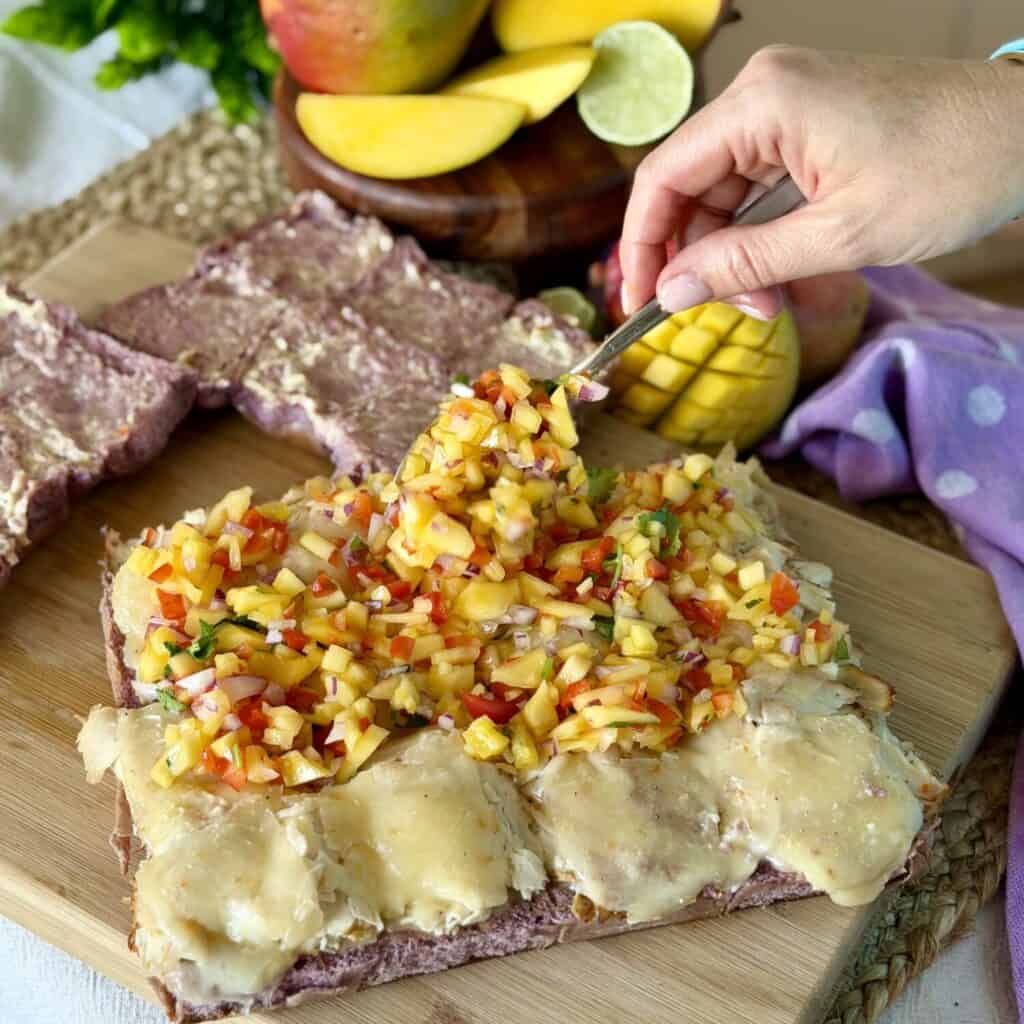 Adding mango salsa to sliders.