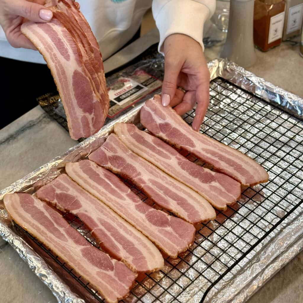 Laying bacon on a tray.