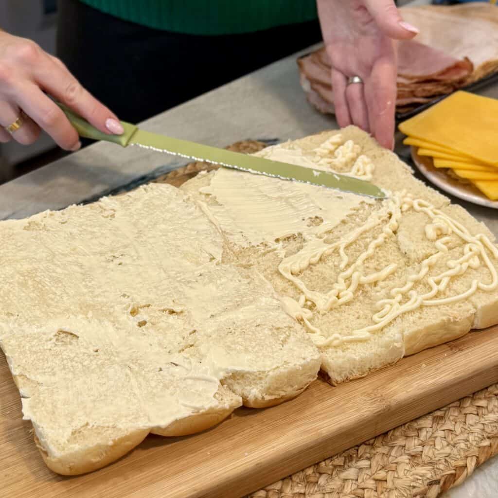 Layering mayo onto the rolls.