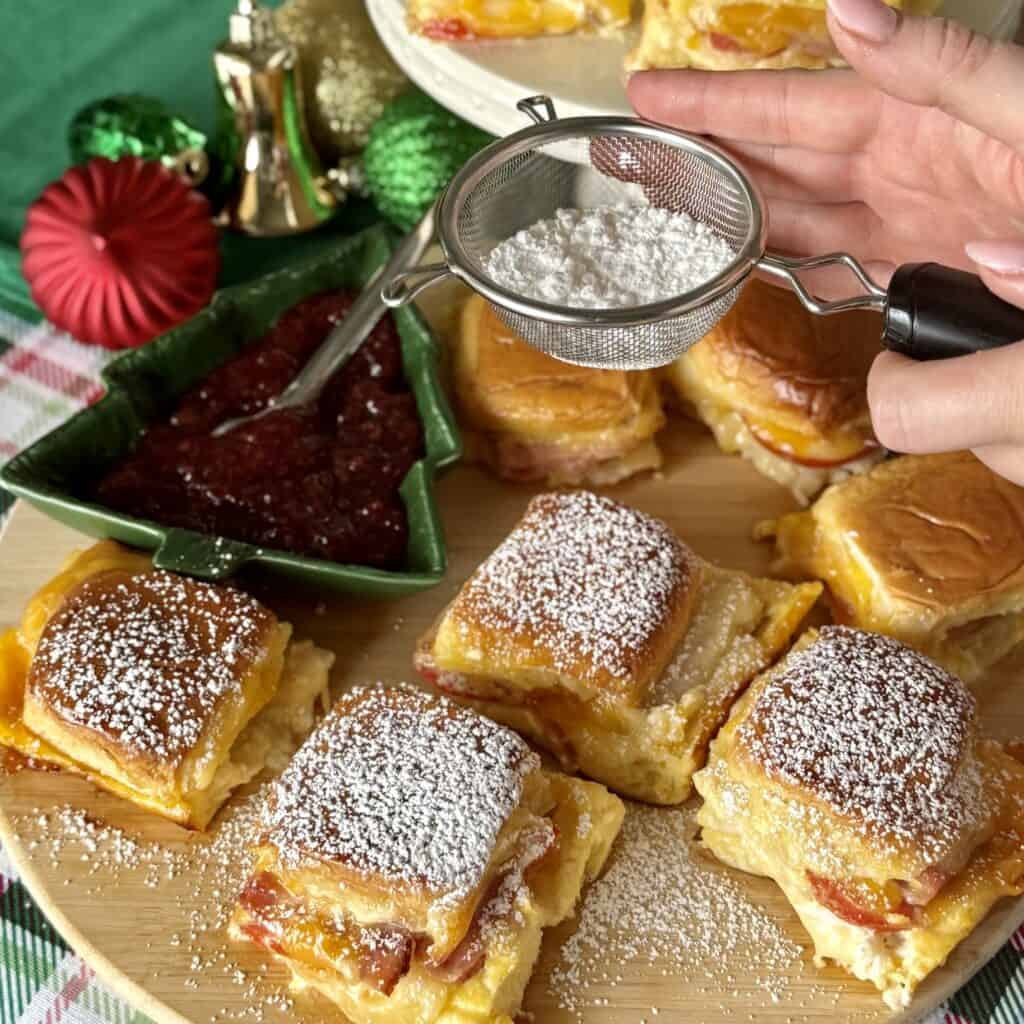 Adding powdered sugar to the Monte Cristo Sliders.