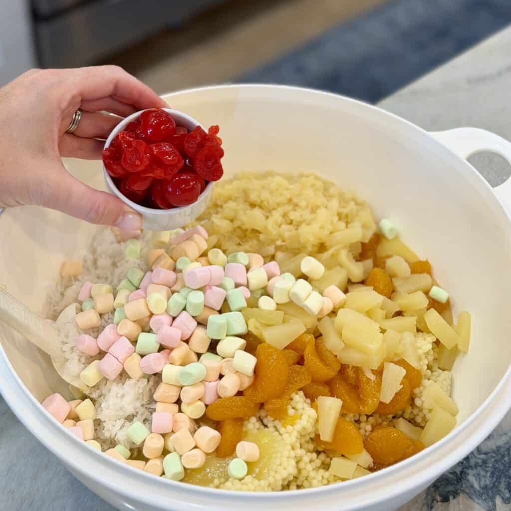 Adding cherries to a bowl of frog eye salad.