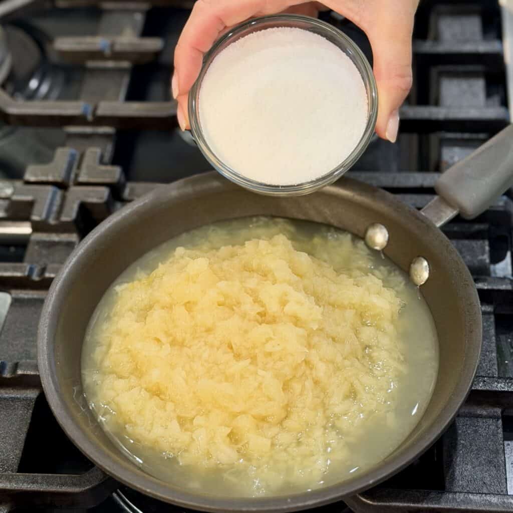Combining sugar and pineapple in a pan.