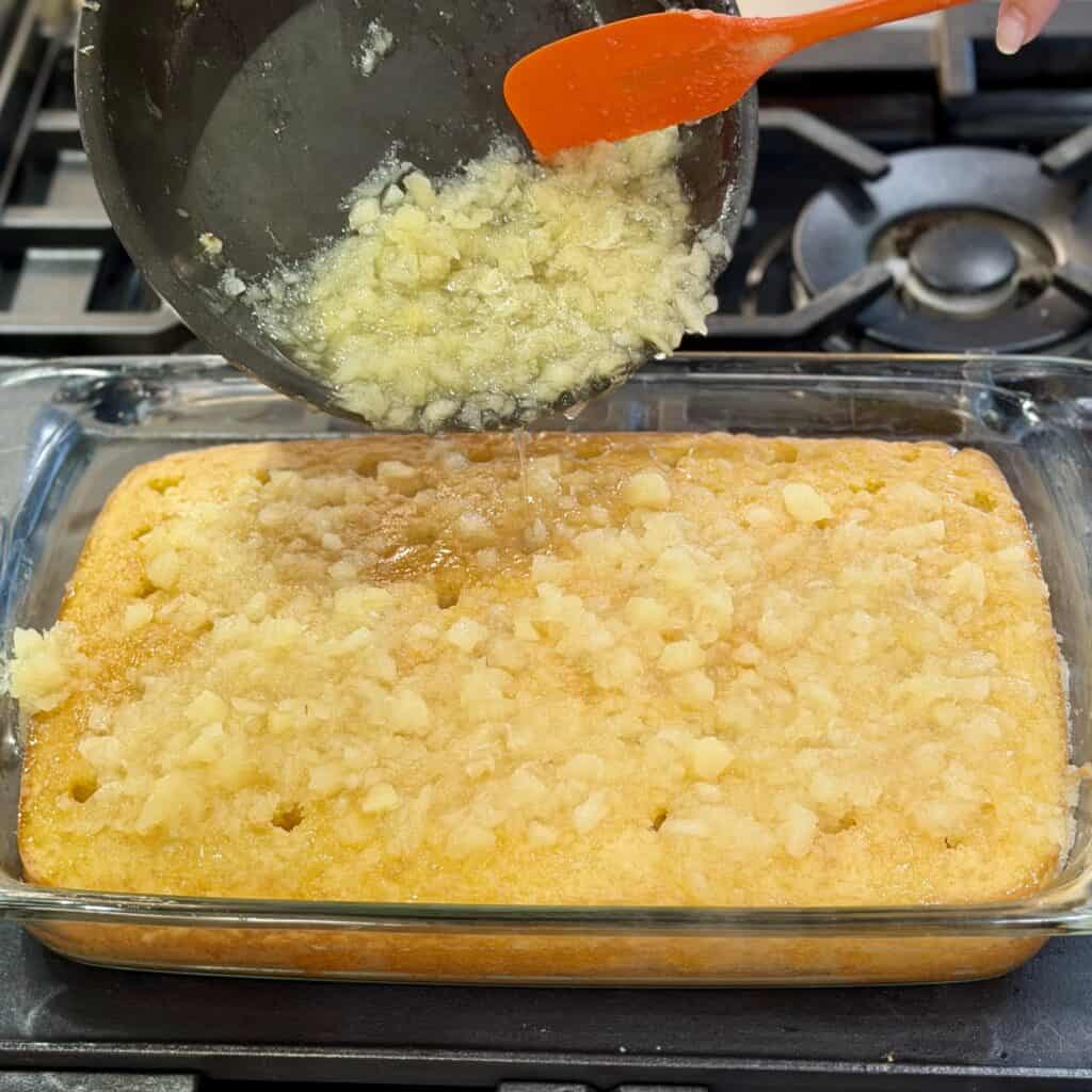 Adding crushed pineapple to the top of a baked cake.