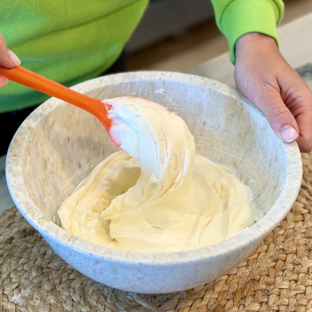 A spatula of frosting in a bowl.