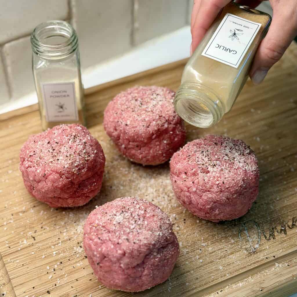 Seasoning beef patties.
