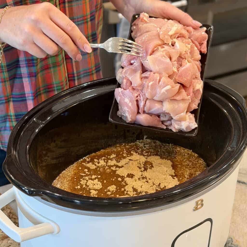 Adding chicken to the crock pot.