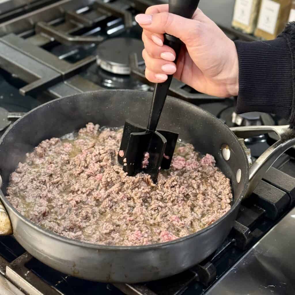 Mashing the beef in to the pan.