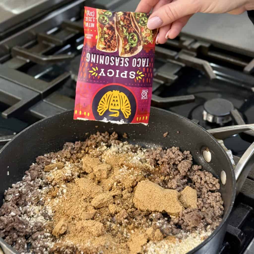 Adding taco seasoning to the pan.