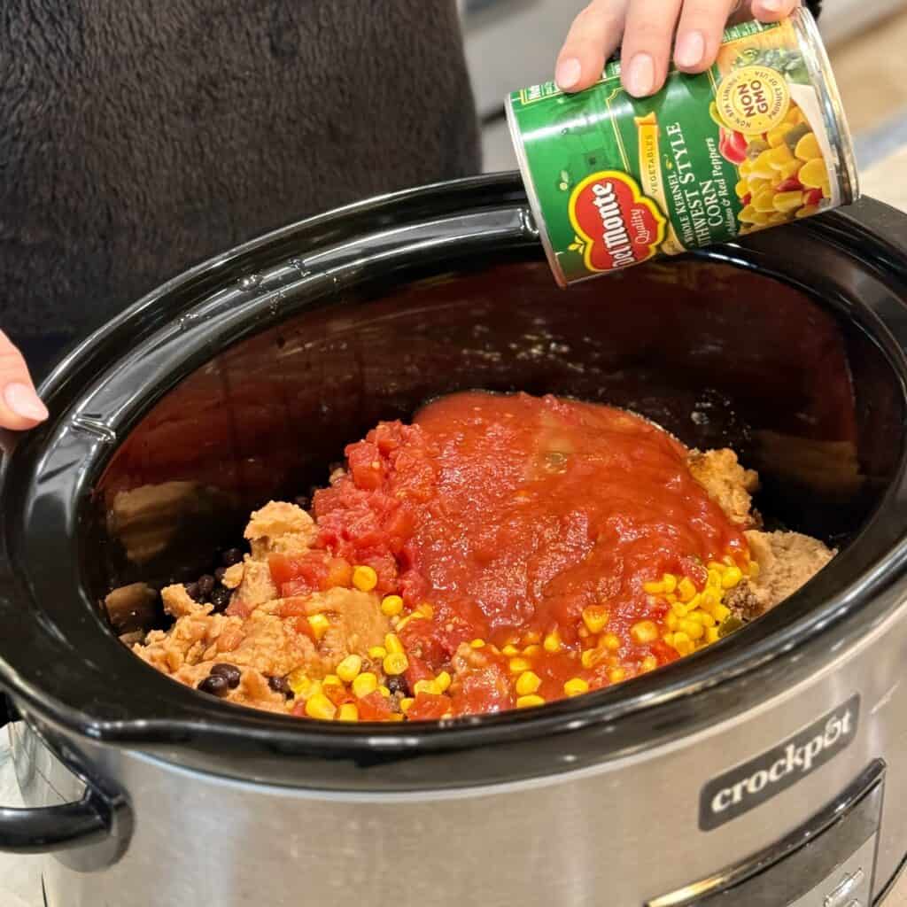 Adding canned tomatoes into the pot.