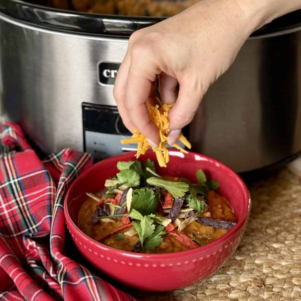 Adding toppings to a bowl of Slow Cooker Taco Soup.