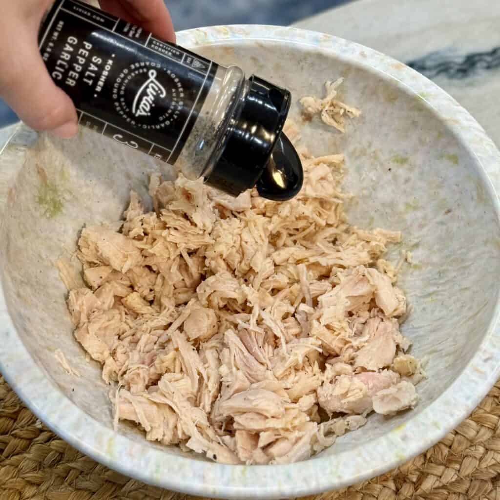 Adding seasoning to the chicken.