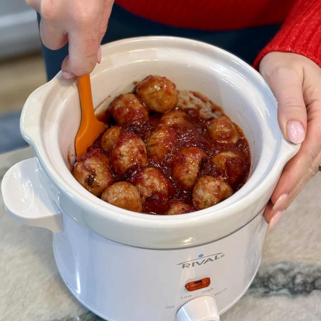 Mixing in meatballs with the sauce mixture.