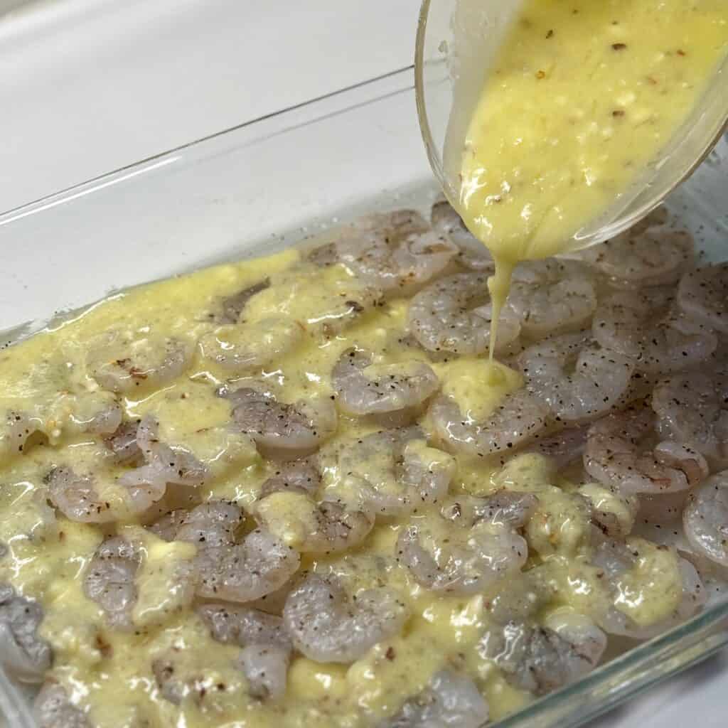 Adding dressing to the pan of shrimp.