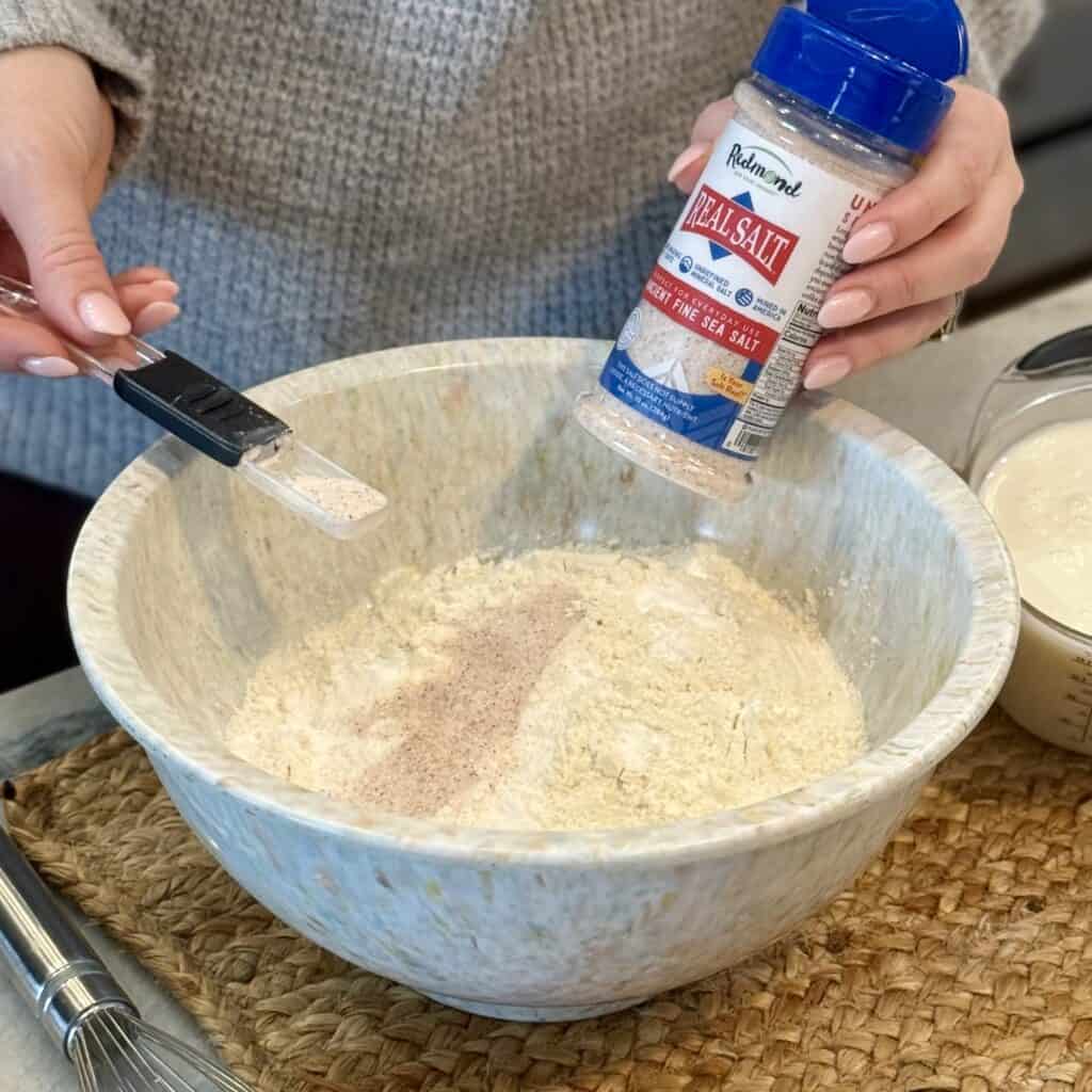 Adding salt into the bowl of flour.
