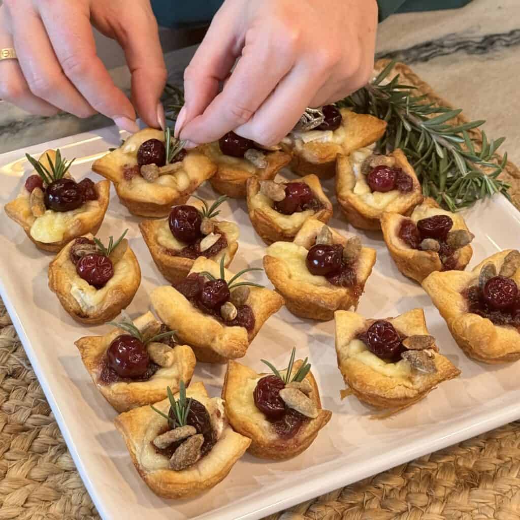 Adding rosemary to brie bites.