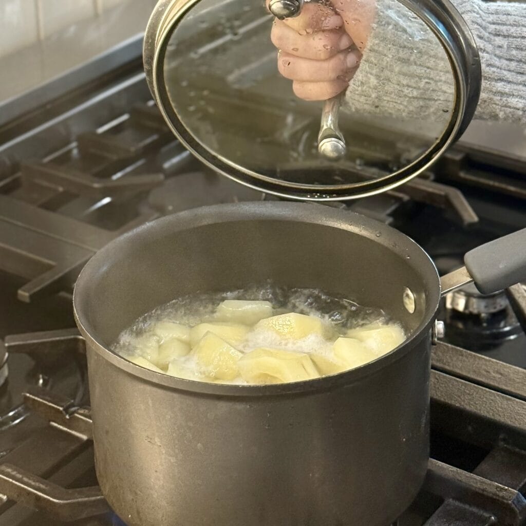 Covering a boiling pan of potatoes.