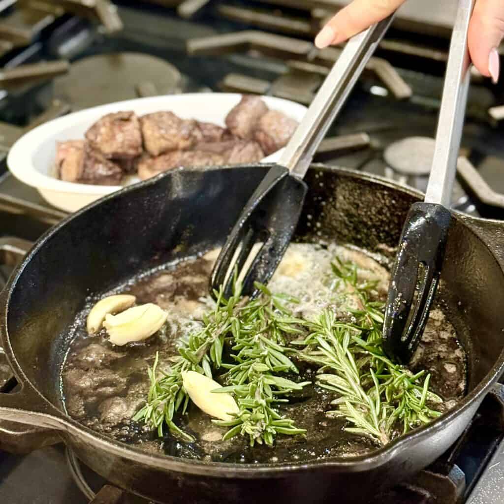Adding garlic and rosemary into the pan.