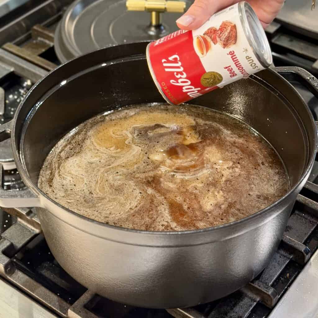 Adding beef broth to the pot.