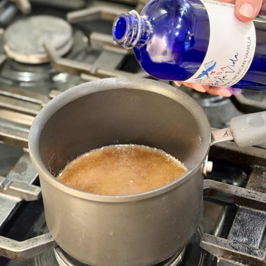 Adding vanilla extract to the pan.